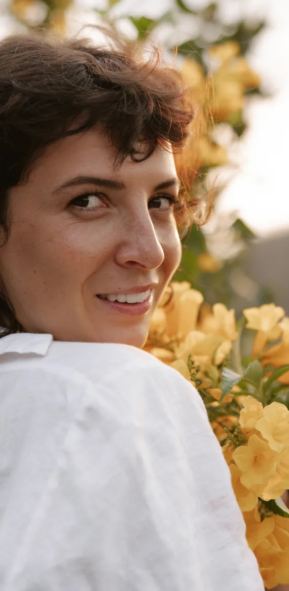 Mulher sorrindo entre flores amarelas